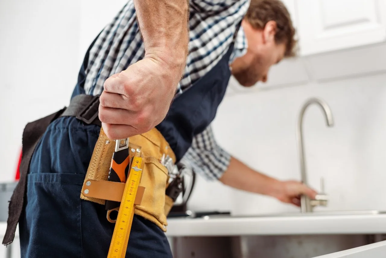 Plumber working on a kitchen sink and tap